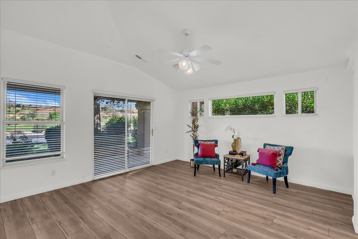 Spacious room featuring wood-finish flooring, a vaulted ceiling, and white painted walls