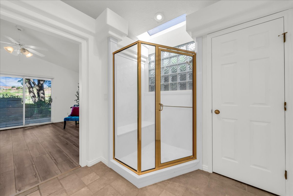 Gold-framed shower enclosure featuring glass block detailing and a built-in bench
