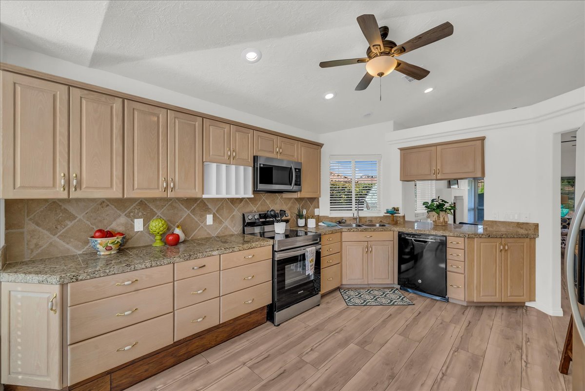 Kitchen featuring wood-finish flooring, light wood cabinetry, stone countertops, a tiled backsplash, and recessed lighting