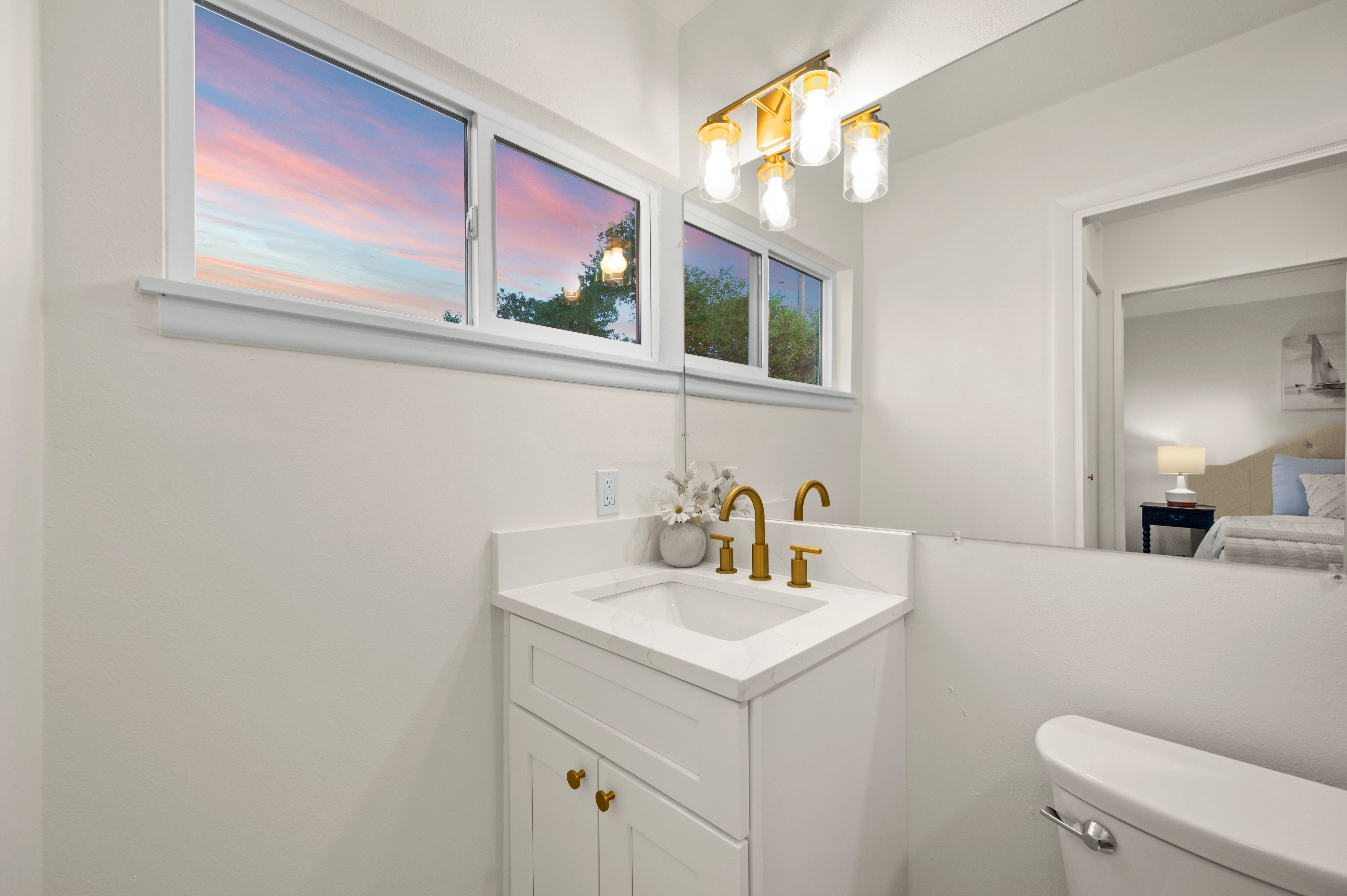 Bathroom featuring a white vanity with gold-tone hardware, a rectangular undermount sink, and a white countertop
