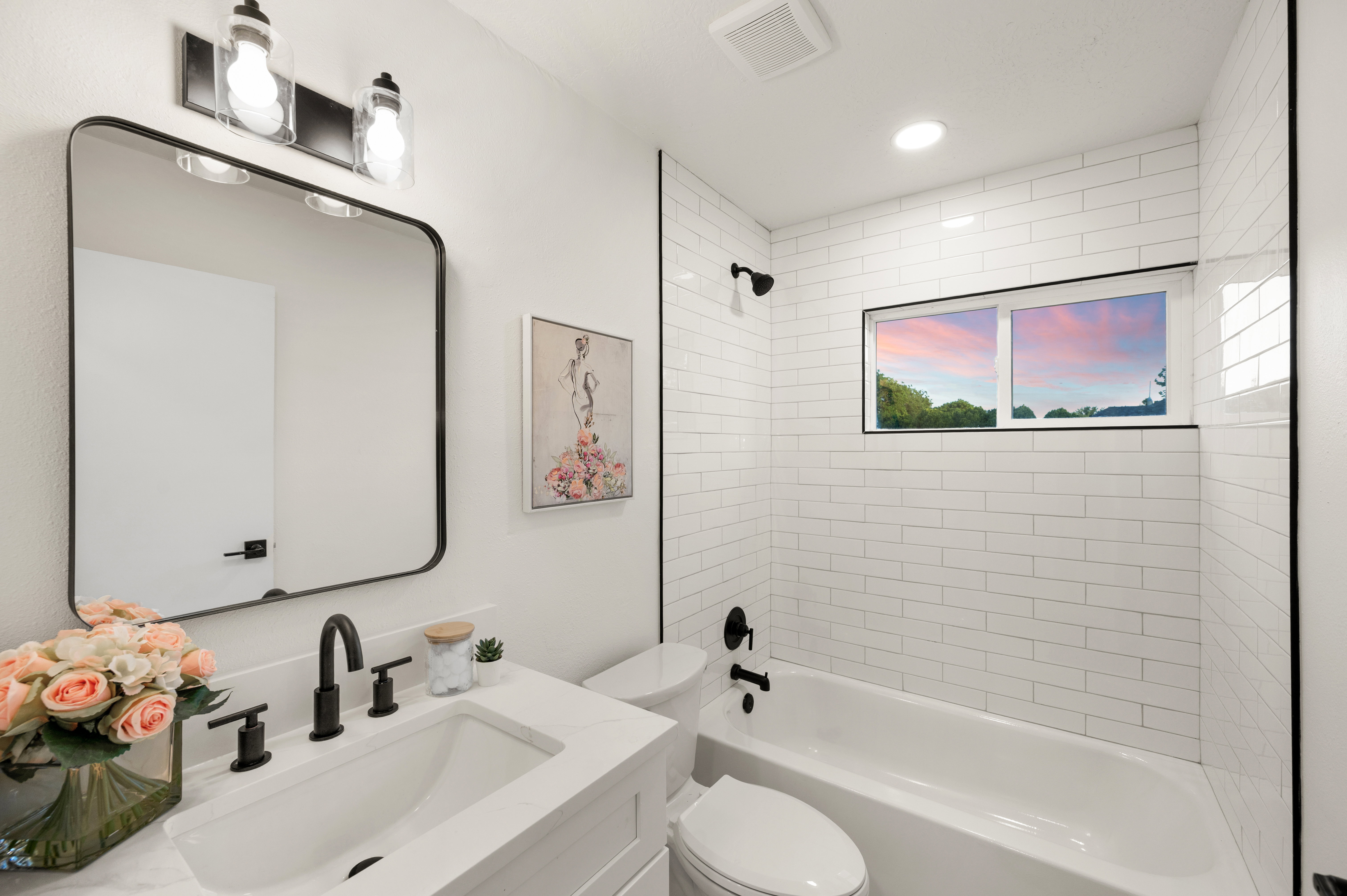 Modern bathroom featuring a white subway tile tub surround, white vanity with quartz-finish countertop, and matte black plumbing fixtures