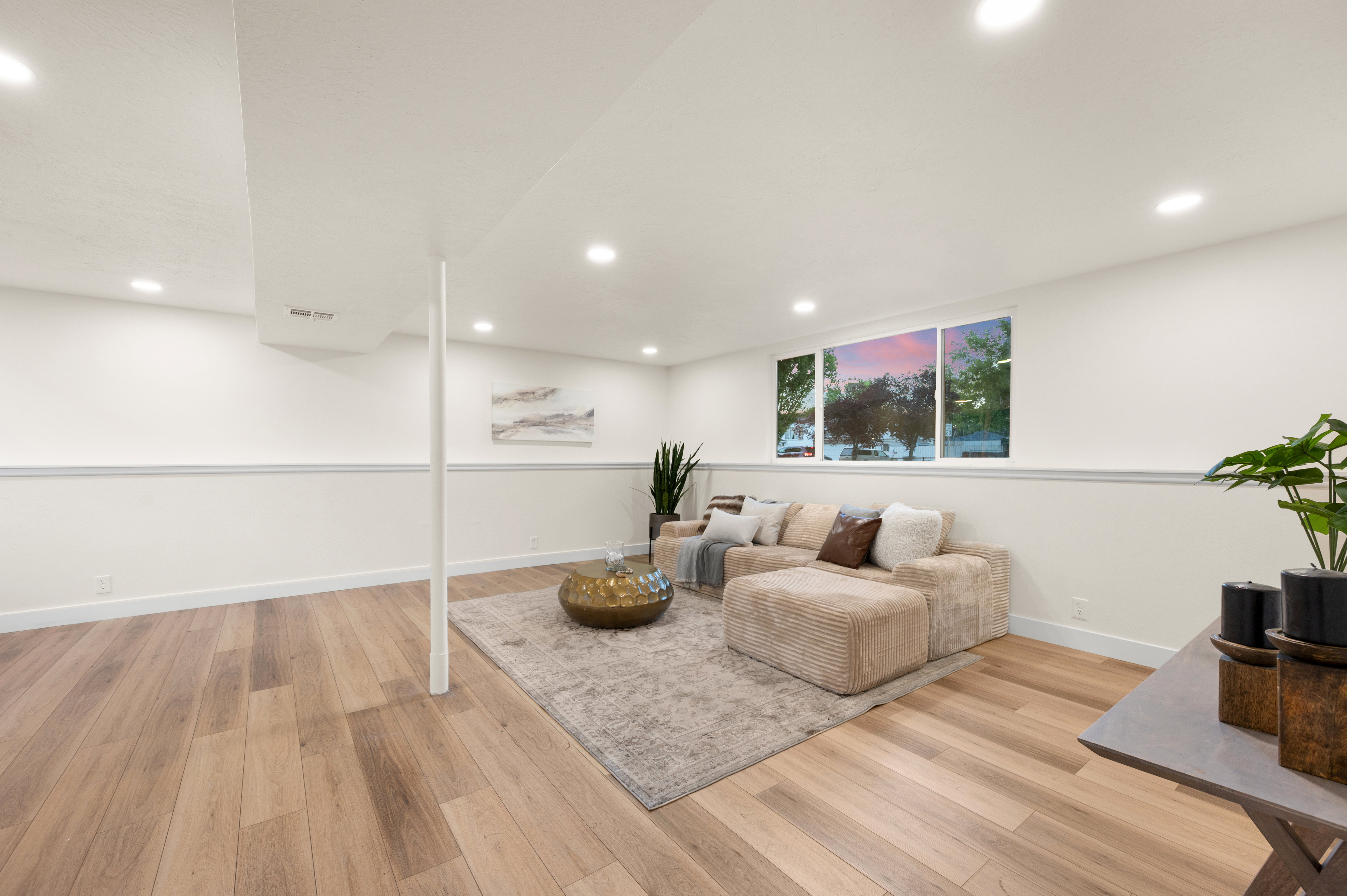 Basement family room. Spacious room featuring wood-finish flooring, recessed lighting, and white baseboards