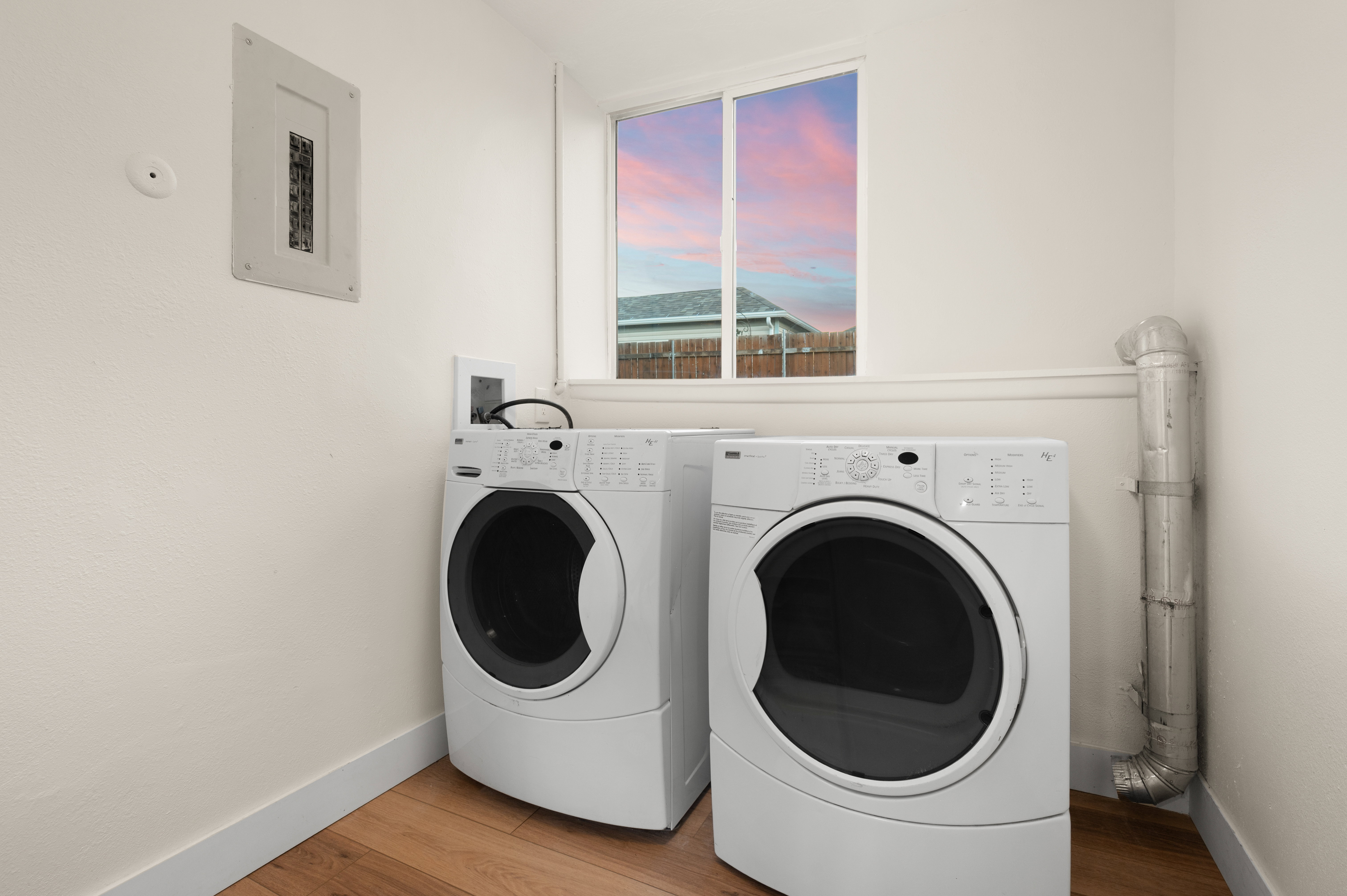Dedicated laundry area featuring wood-finish flooring and a white window frame