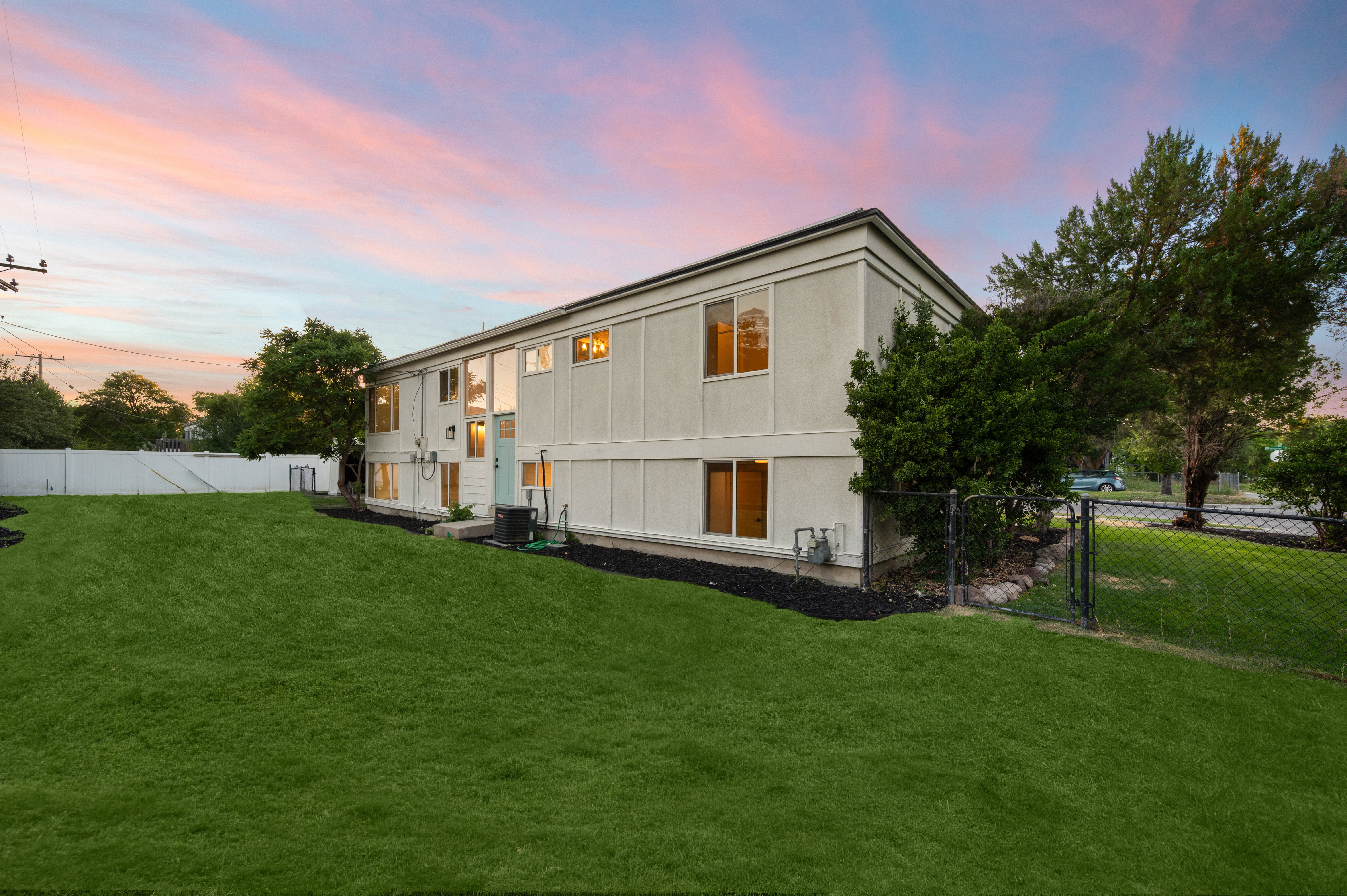 Expansive green lawn with a white privacy fence and chain link fencing