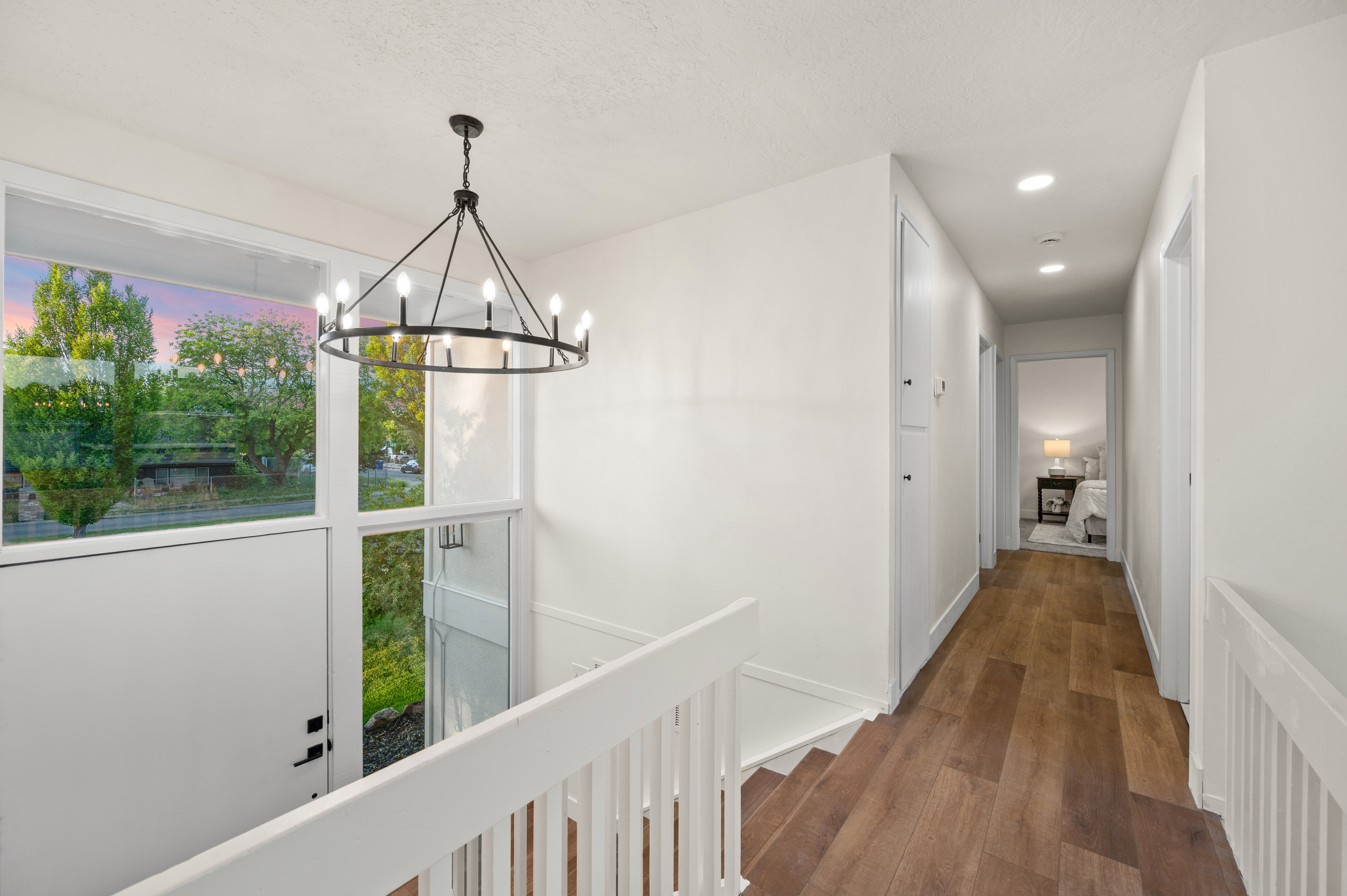 Upper-level hallway featuring wood-finish flooring, recessed lighting, and a modern chandelier