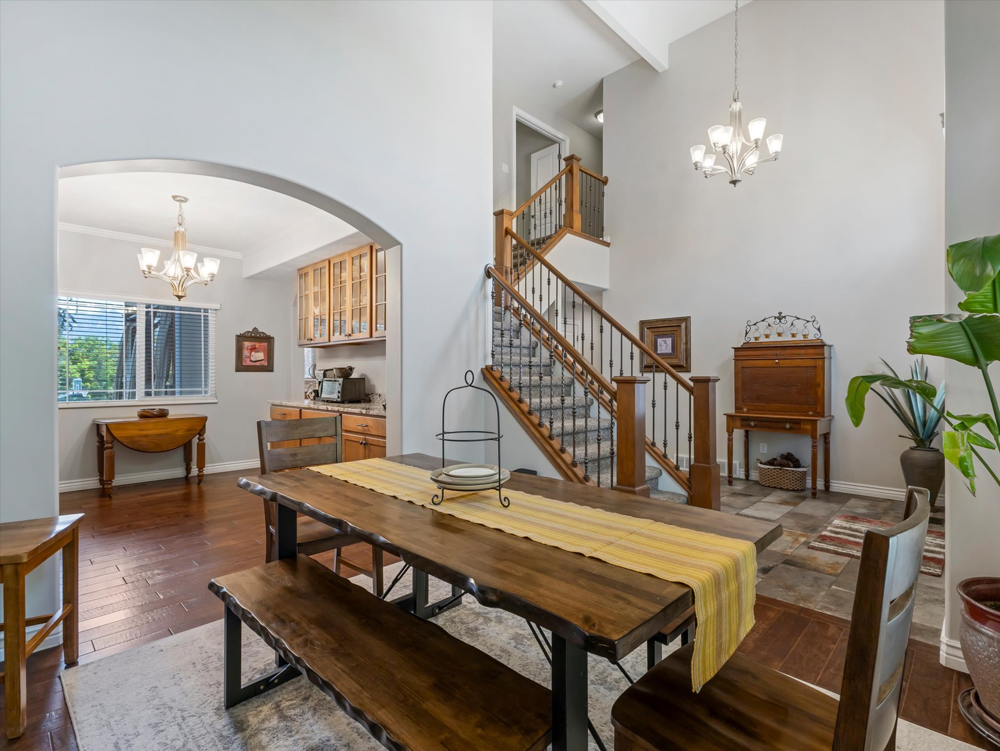 Open-concept living area featuring a grand staircase with wrought iron balusters, hardwood flooring, and a formal dining space