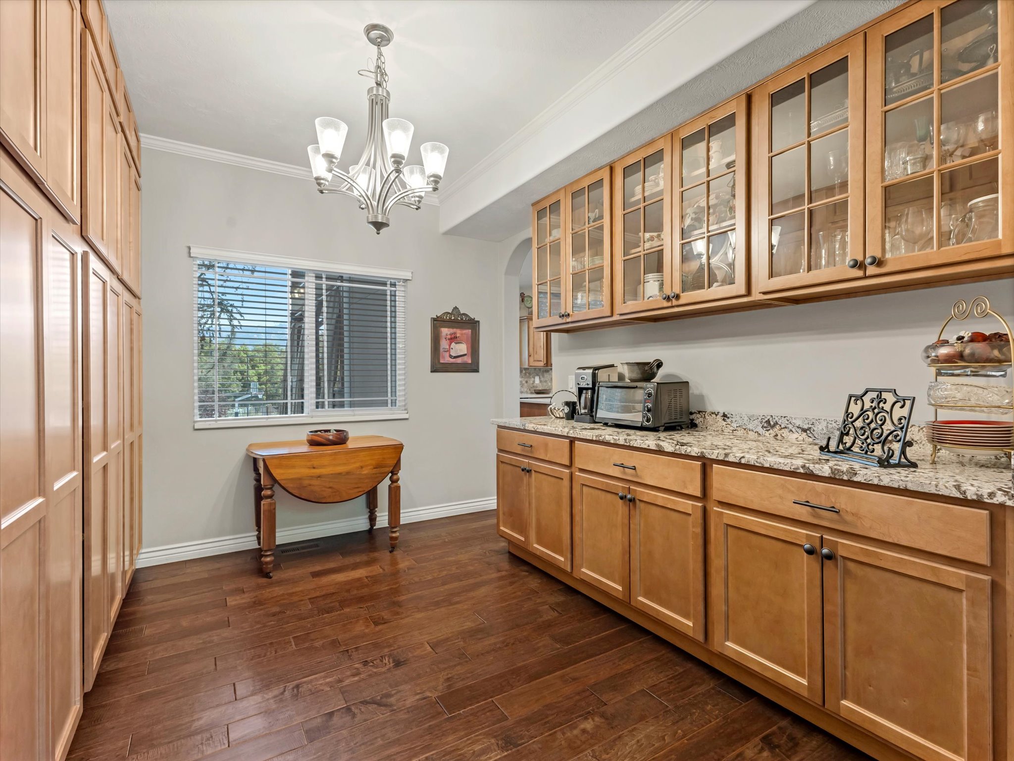 Butler's pantry with extensive built-in cabinetry with glass-front uppers and solid wood-finish lowers