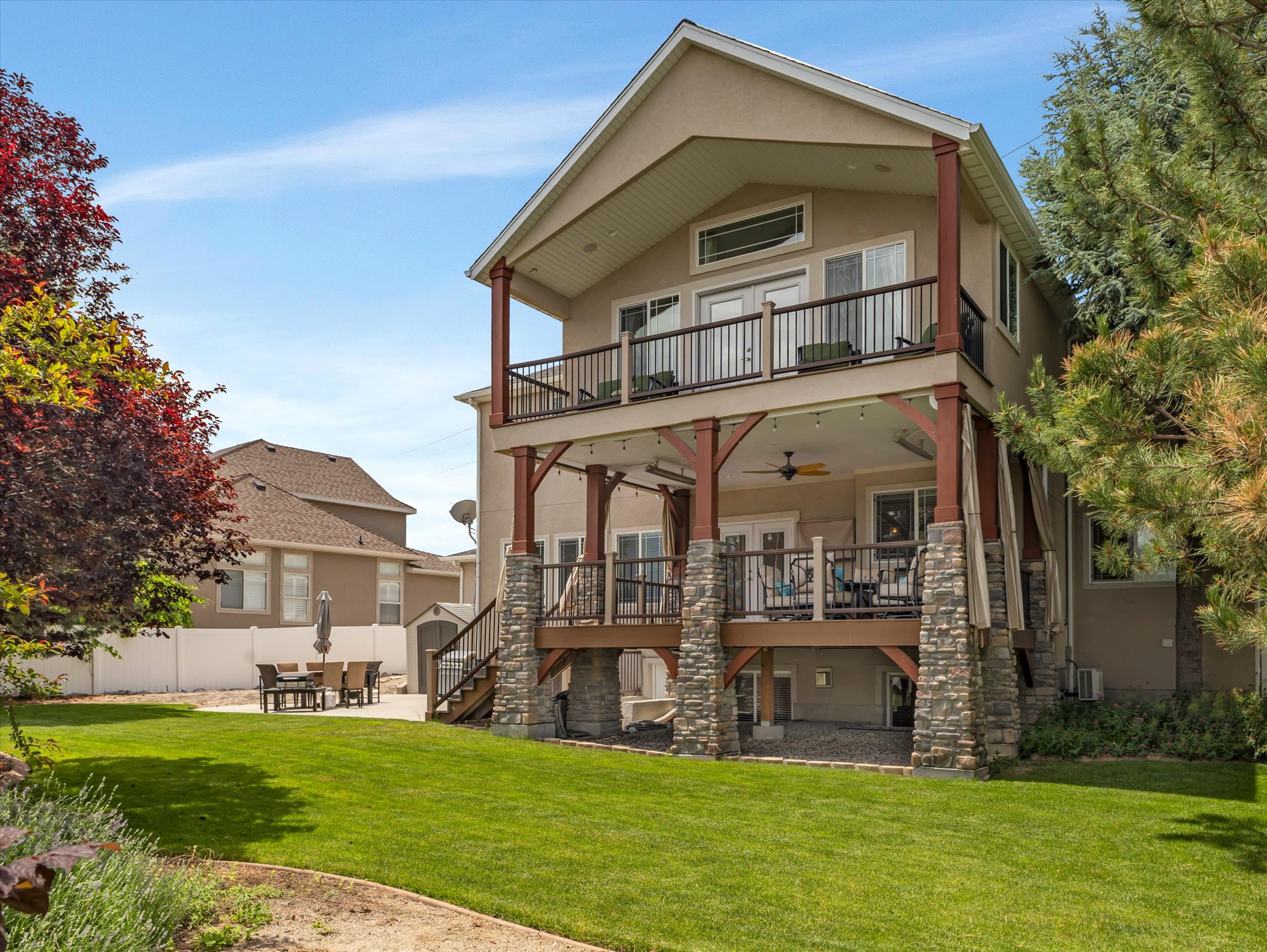 Back view of the house with upper and lower decks and an outdoor patio.