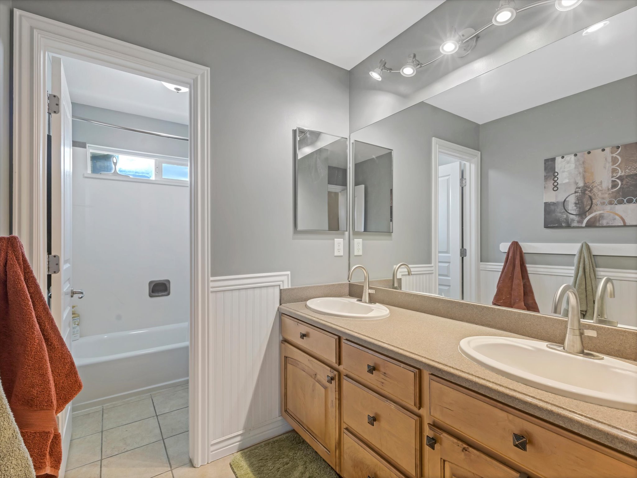 Second floor bathroom featuring a double vanity with wood-finish cabinetry, integrated sinks, and separate water closet.