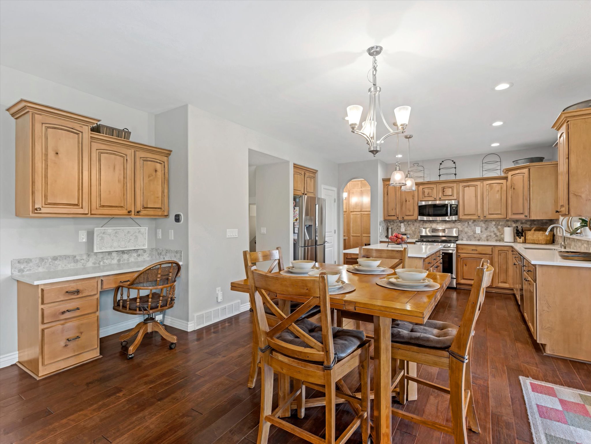 Gourmet kitchen with wood-finish flooring, light wood cabinetry, stone countertops, and stainless steel appliances