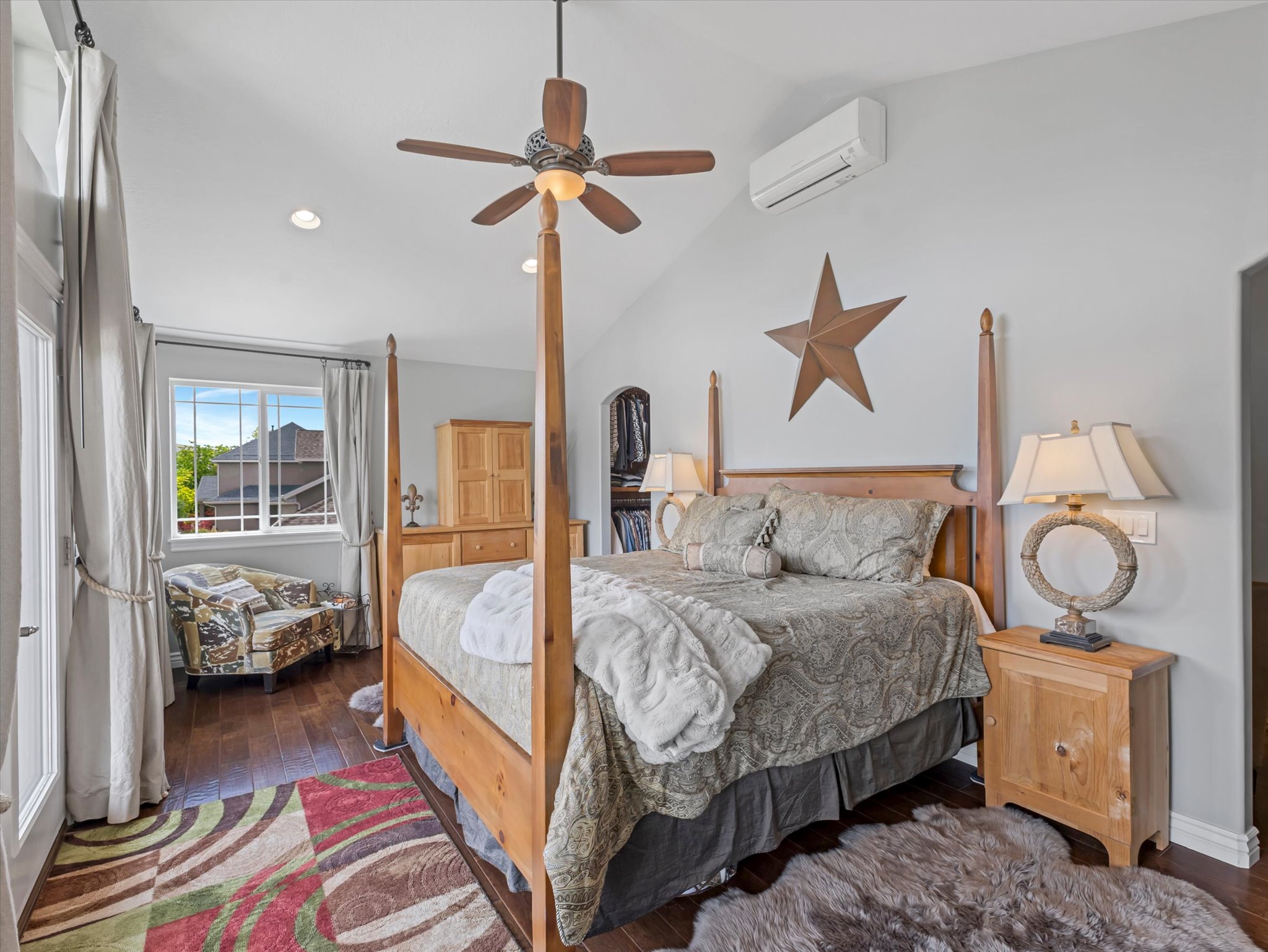 Primary suite bedroom with vaulted ceilings, wood-finish flooring, recessed lighting, a ceiling fan and a dedicated mini-split HVAC system