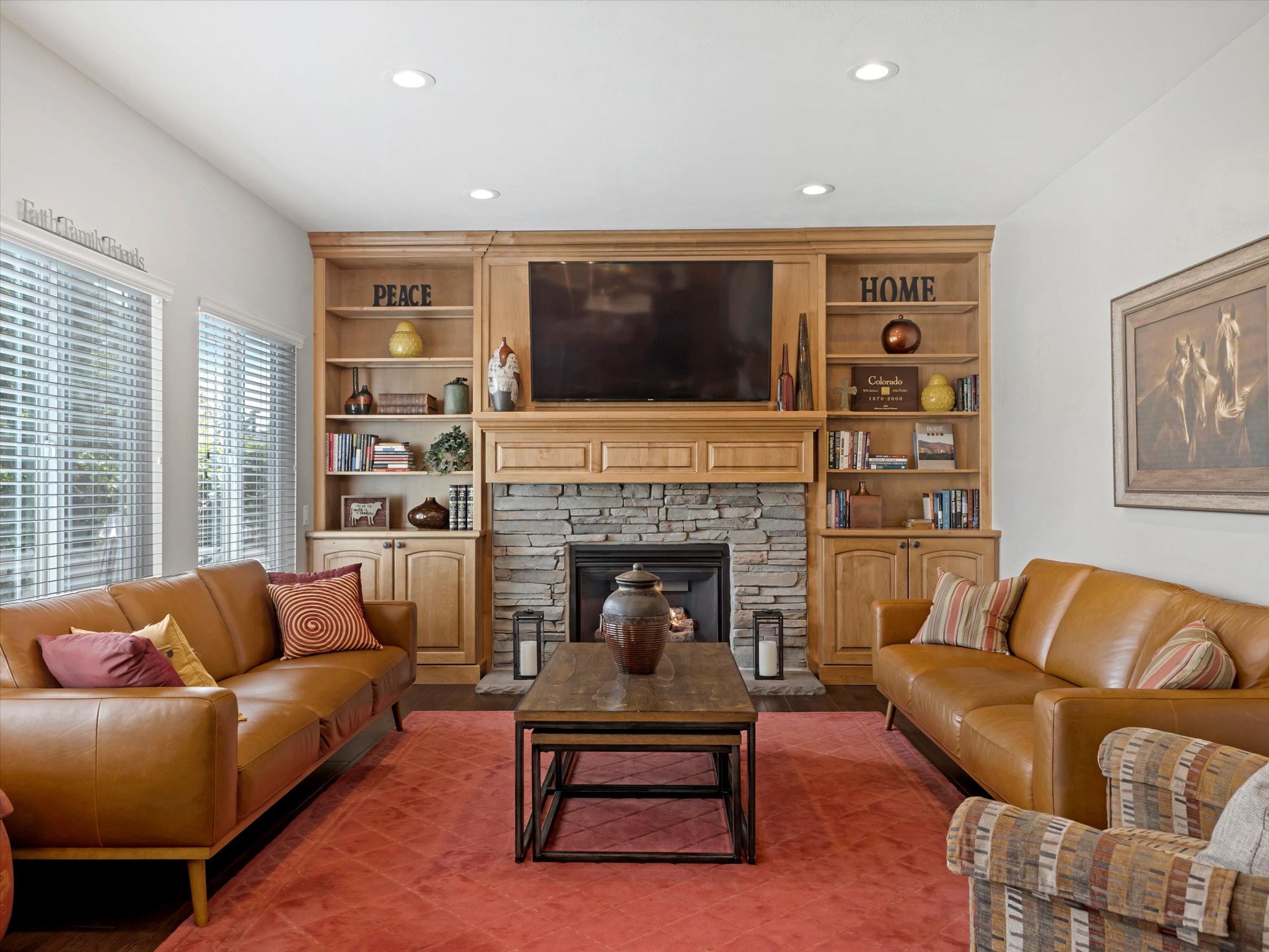 Living area featuring a stone-clad fireplace with a wood mantel, built-in wood cabinetry, recessed lighting, and wood-finish flooring
