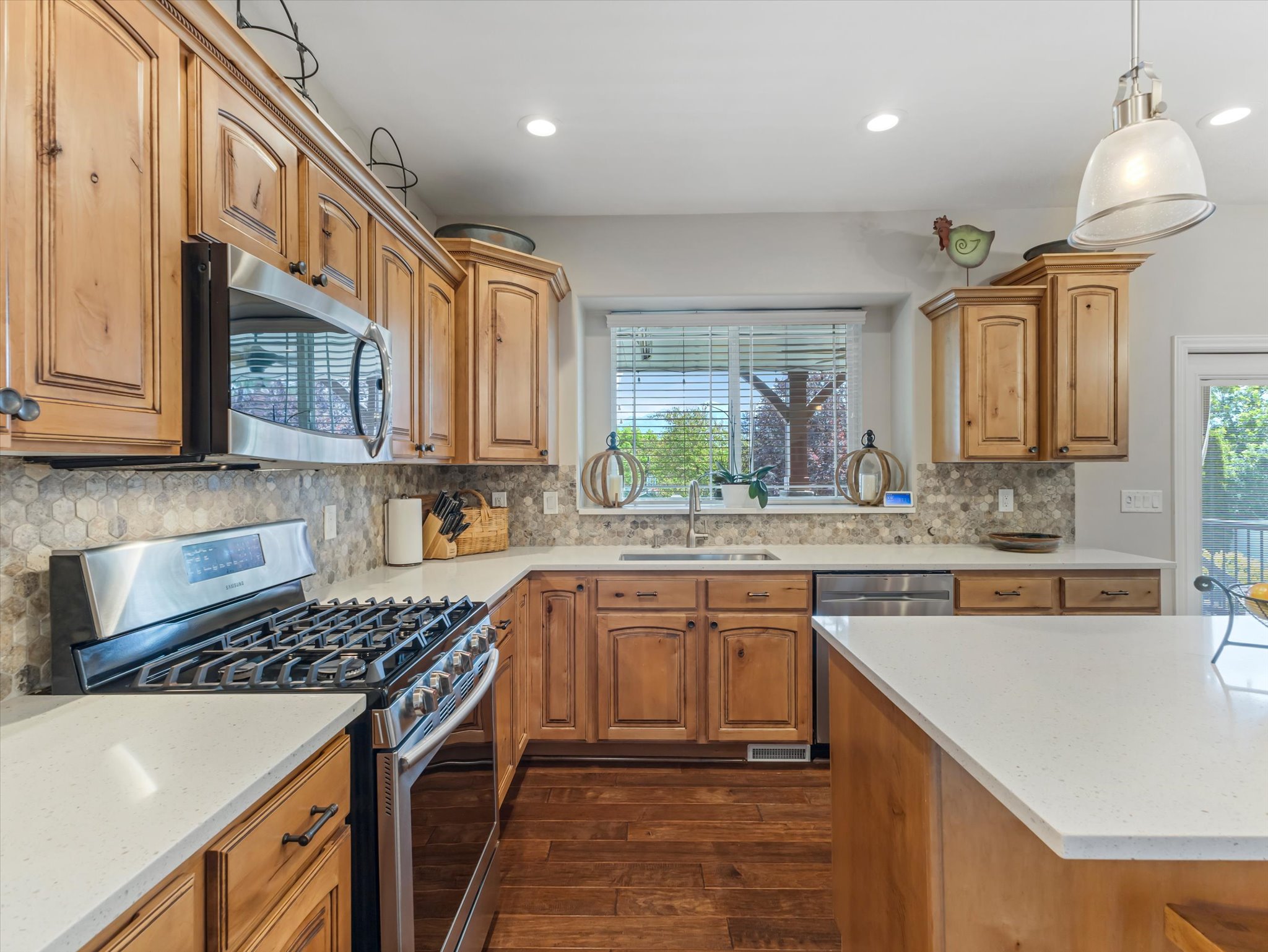 Kitchen featuring wood cabinetry, stainless steel appliances, white granite countertops, and a tile backsplash