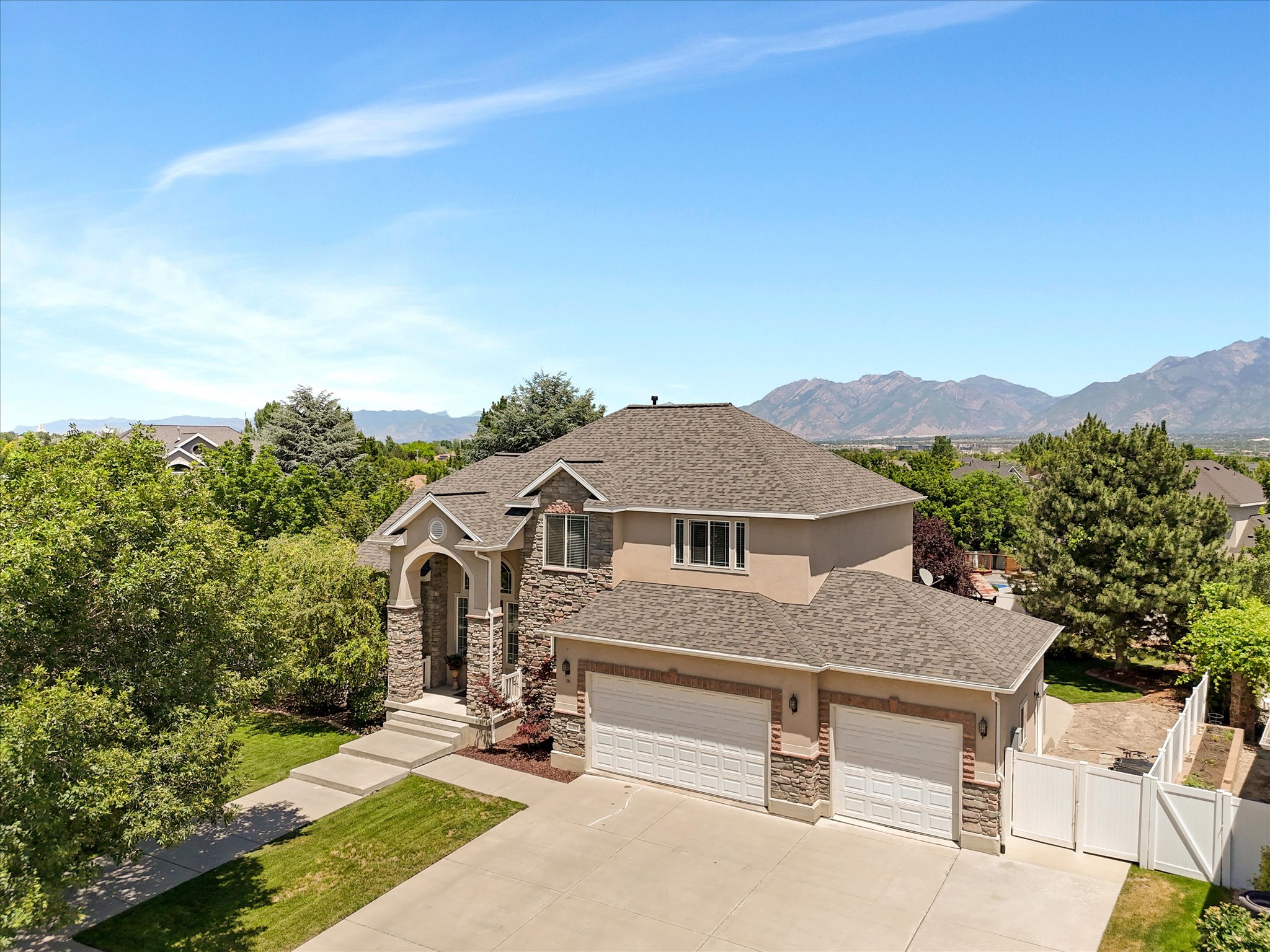 Stately two-story residence featuring a stone and stucco exterior, a three-car garage, and a concrete driveway
