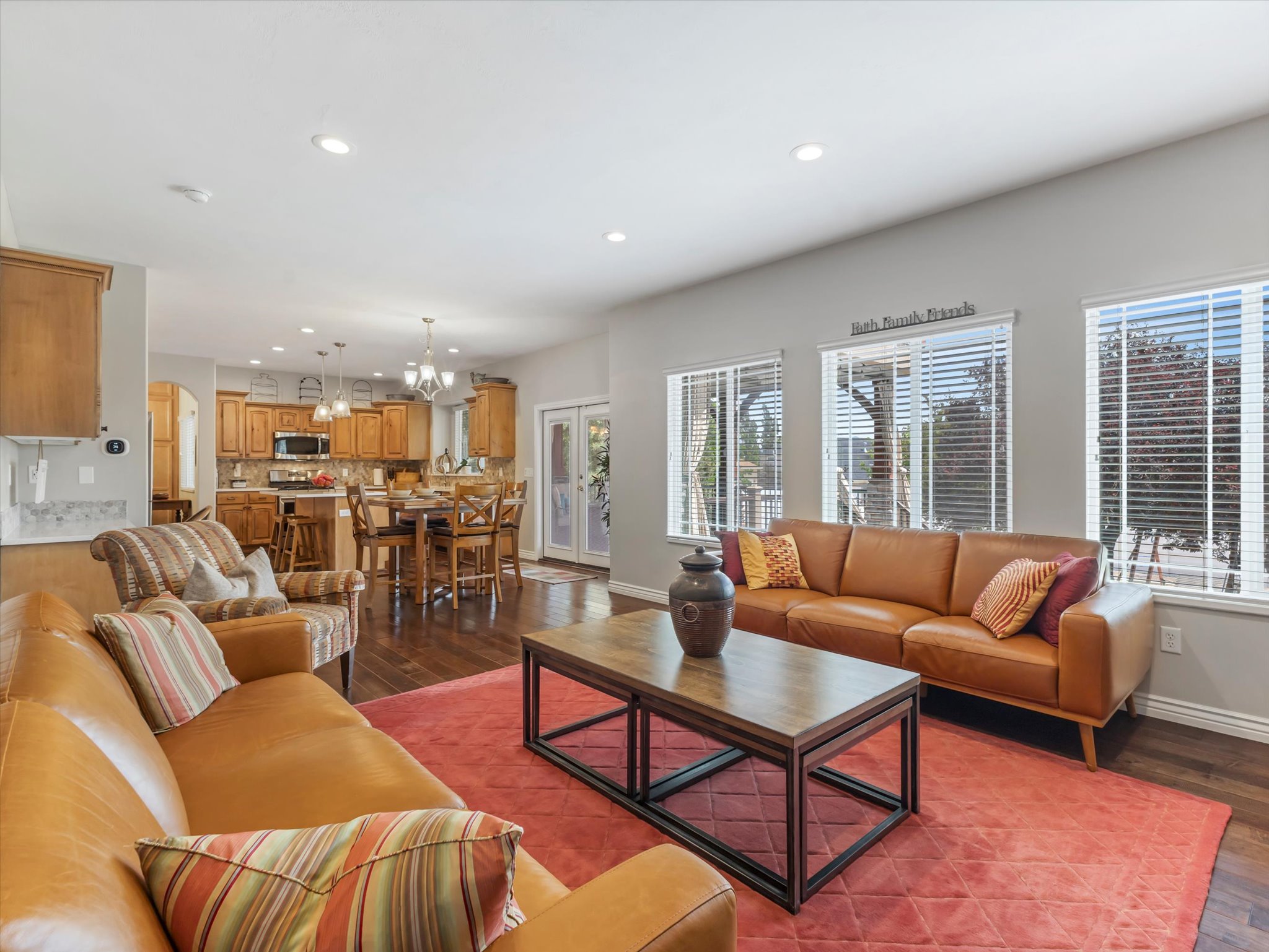Open concept living space featuring wood-finish flooring, recessed lighting, and multiple windows with blinds
