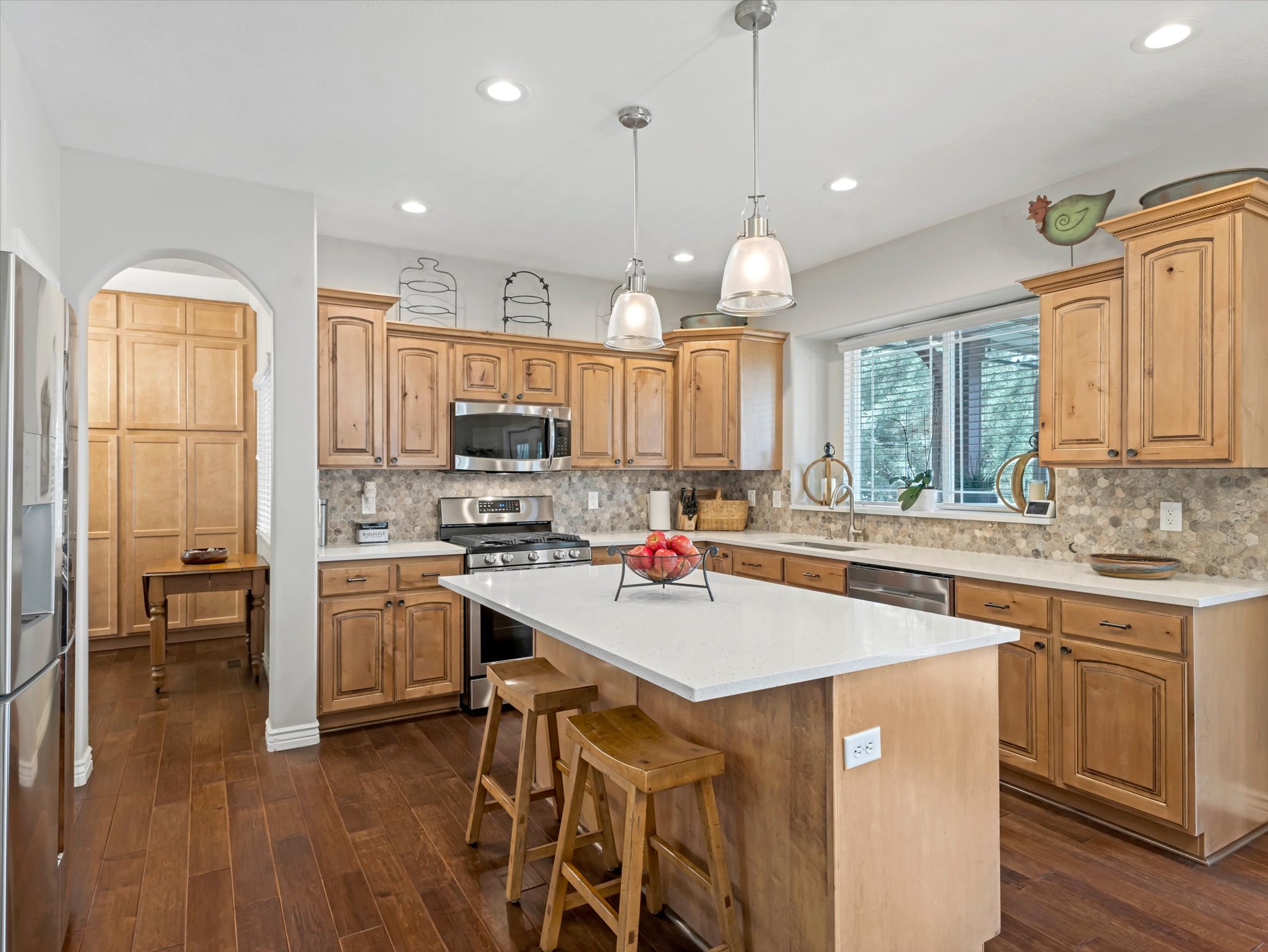 Kitchen featuring warm wood cabinetry, stainless steel appliances, a center island with countertop seating, and recessed lighting
