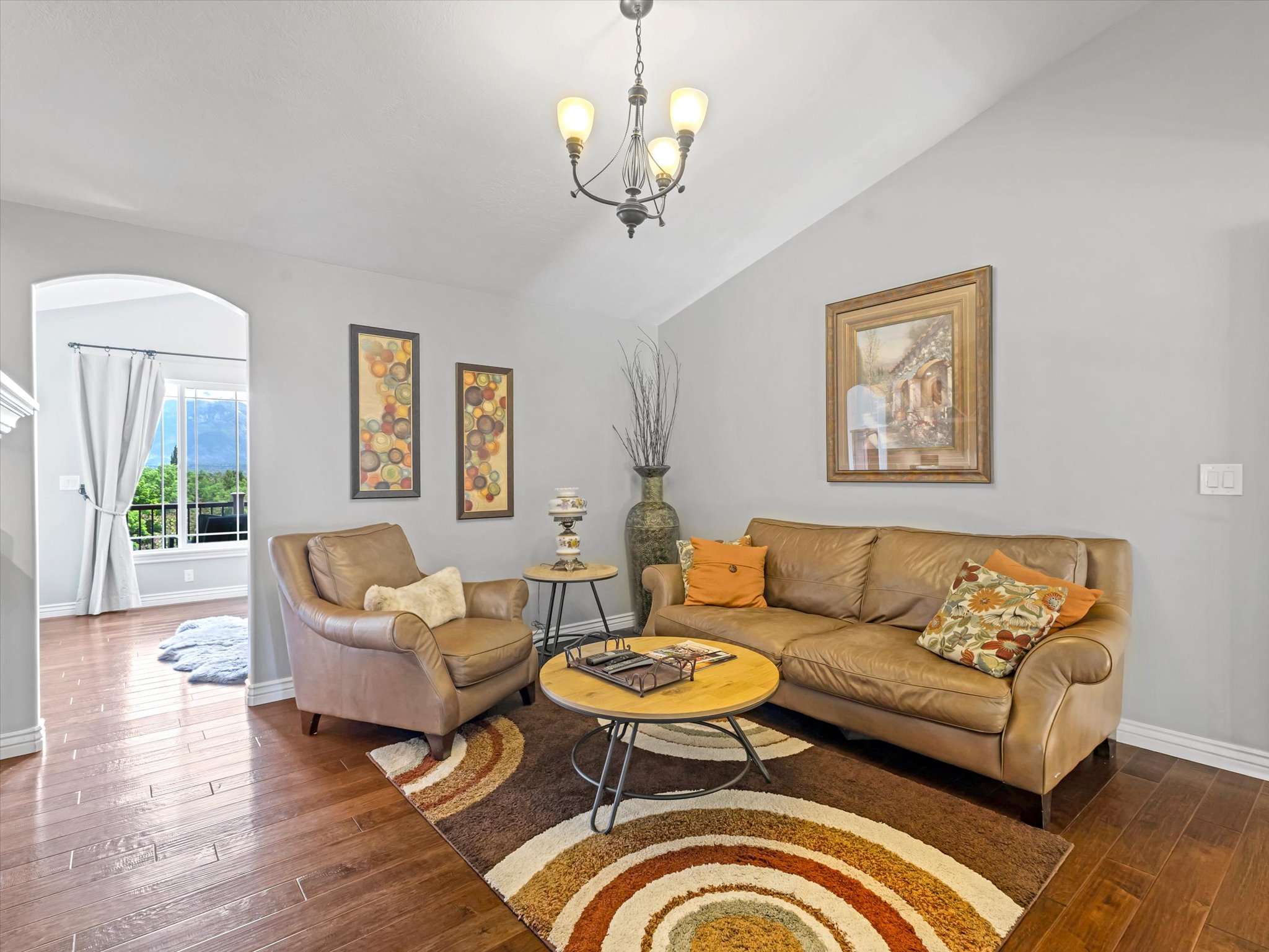 Primary suite living area featuring wood-finish flooring, vaulted ceilings, and an arched doorway