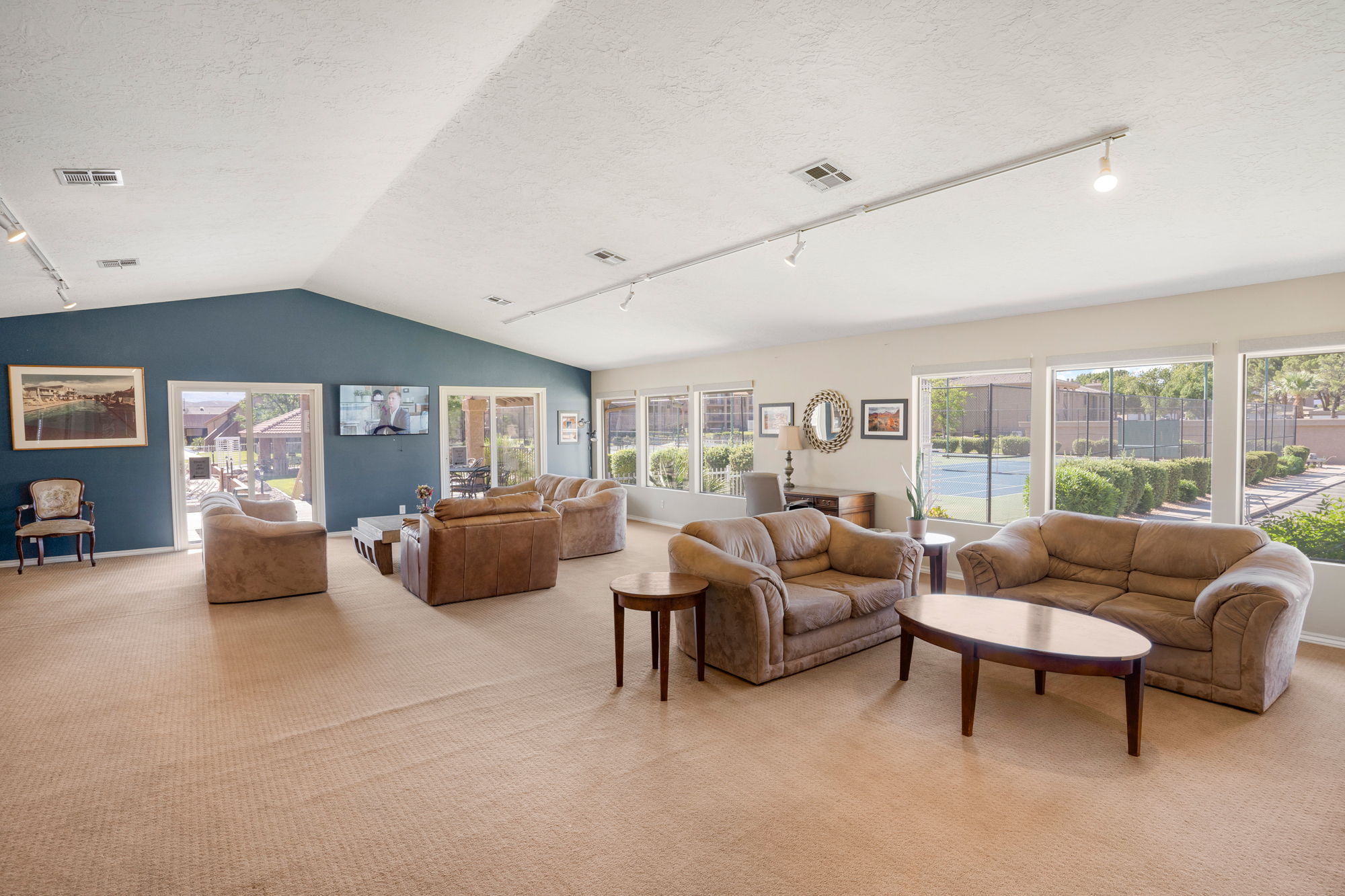 Spacious lounge area featuring a vaulted ceiling and track lighting