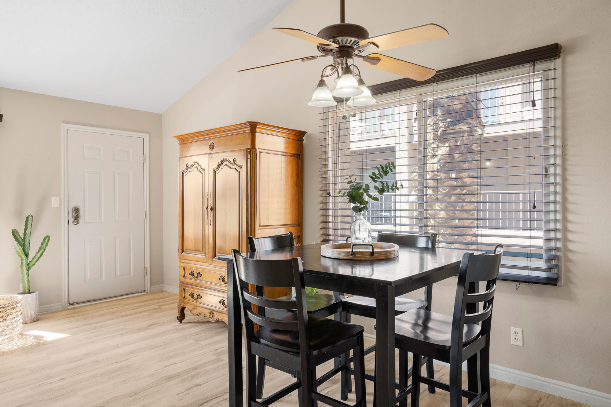 Vaulted ceilings with a ceiling fan light fixture, light wood-finish flooring, and a window with horizontal blinds