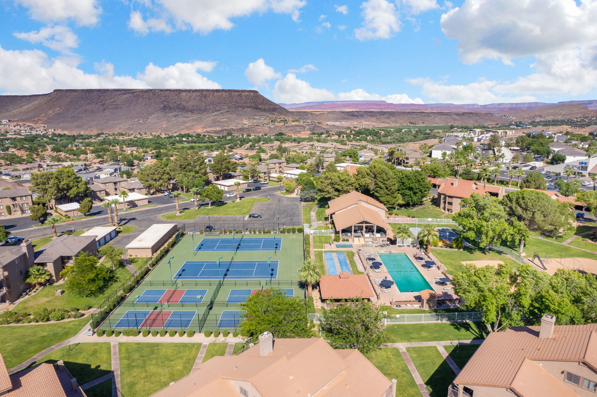 Community amenities featuring multiple tennis courts, a swimming pool, and a clubhouse with a covered patio