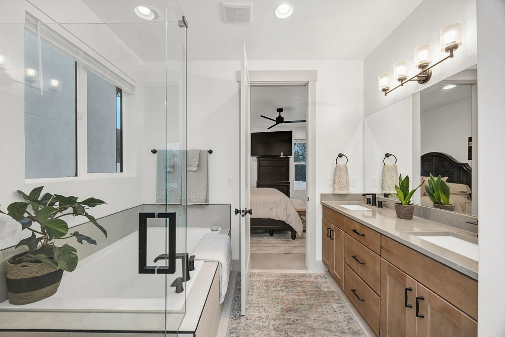 Bathroom featuring a double vanity with light wood cabinetry, white sinks, and a light-toned countertop
