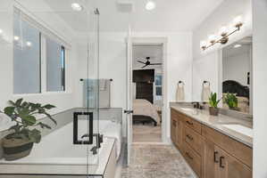 Bathroom featuring a double vanity with light wood cabinetry, white sinks, and a light-toned countertop
