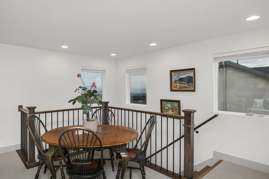 Open loft area featuring a wood-finish railing with black metal spindles and multiple windows