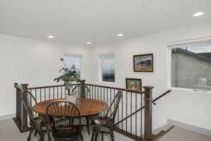 Open loft area featuring a wood-finish railing with black metal spindles and multiple windows