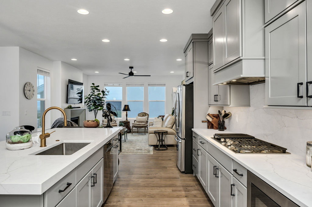 Modern kitchen featuring light gray cabinetry, white countertops, and a gold-finish faucet