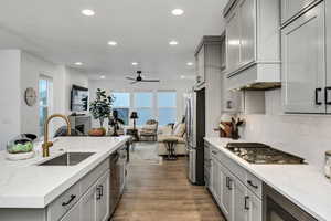 Modern kitchen featuring light gray cabinetry, white countertops, and a gold-finish faucet