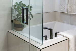 Soaking tub with a matte black deck-mounted faucet and separate controls