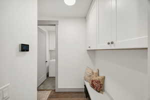 Entryway mudroom featuring white shaker-style cabinetry with satin nickel hardware, a built-in bench, and wood-finish flooring