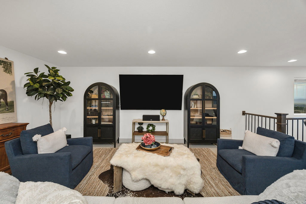 Bright living area featuring recessed lighting, a mounted wall screen, and white walls