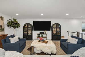 Bright living area featuring recessed lighting, a mounted wall screen, and white walls