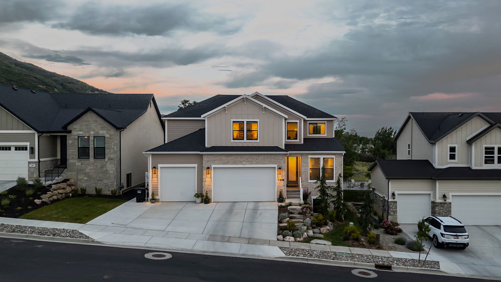 Contemporary two-story residence featuring light siding and stone veneer accents