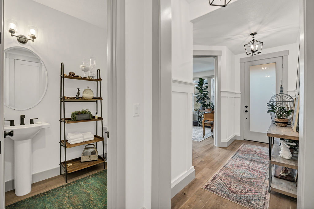 Hallway featuring wood-finish flooring, wainscoting, and a panel door with frosted glass