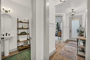 Hallway featuring wood-finish flooring, wainscoting, and a panel door with frosted glass