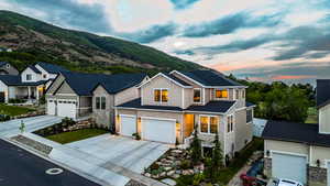 Contemporary architectural style with a stone and siding facade, featuring a two-car garage, established landscaping, and a mountain backdrop