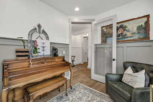 Light gray wainscoting and crown molding accent an interior space with wood-finish flooring
