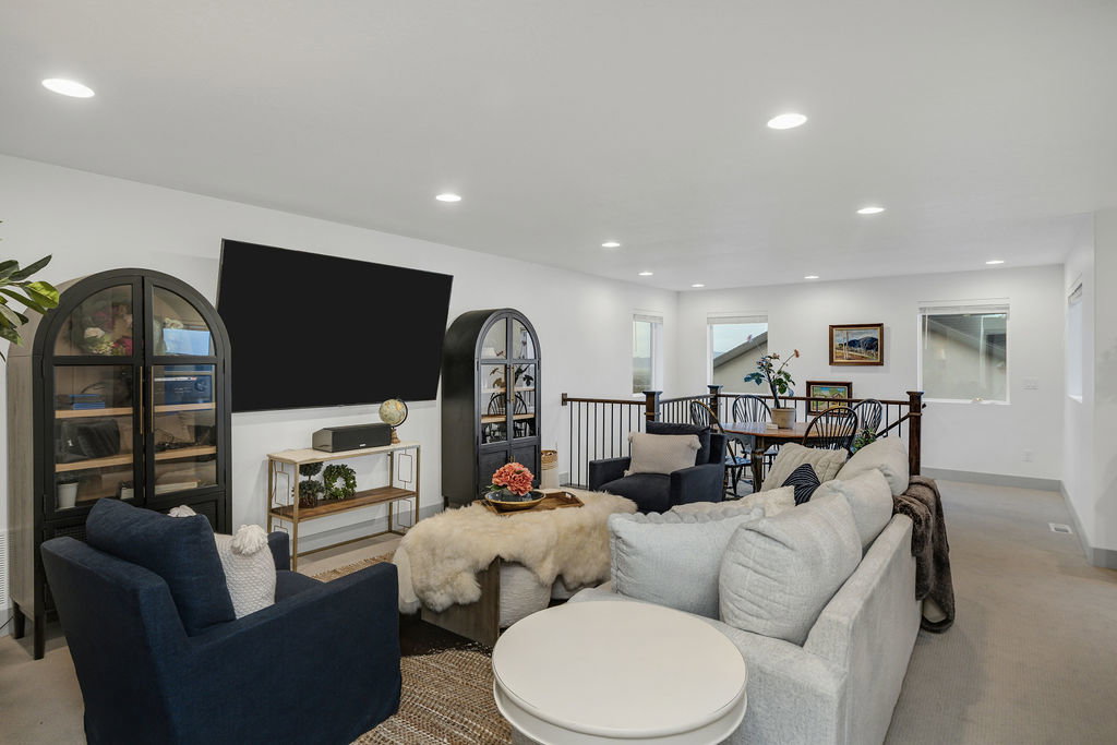 Spacious living area featuring recessed lighting, light-colored walls, and a railing overlooking a dining area