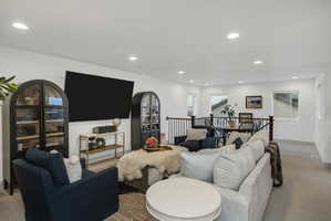 Spacious living area featuring recessed lighting, light-colored walls, and a railing overlooking a dining area