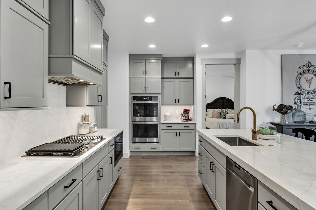 Kitchen featuring light gray cabinetry, light-toned countertops, wood-finish flooring, recessed lighting, and stainless steel appliances
