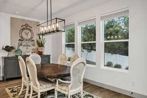 Dining area featuring wood-finish flooring, a linear chandelier, and a built-in sideboard