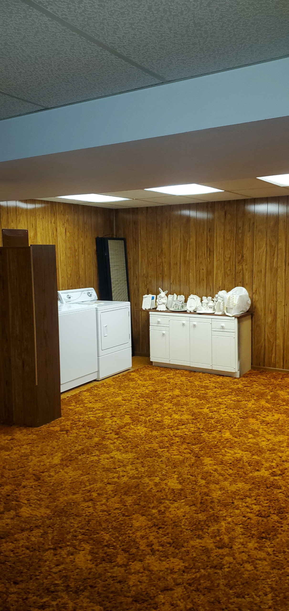 Utility area featuring wood-paneled walls and a drop ceiling with integrated lighting