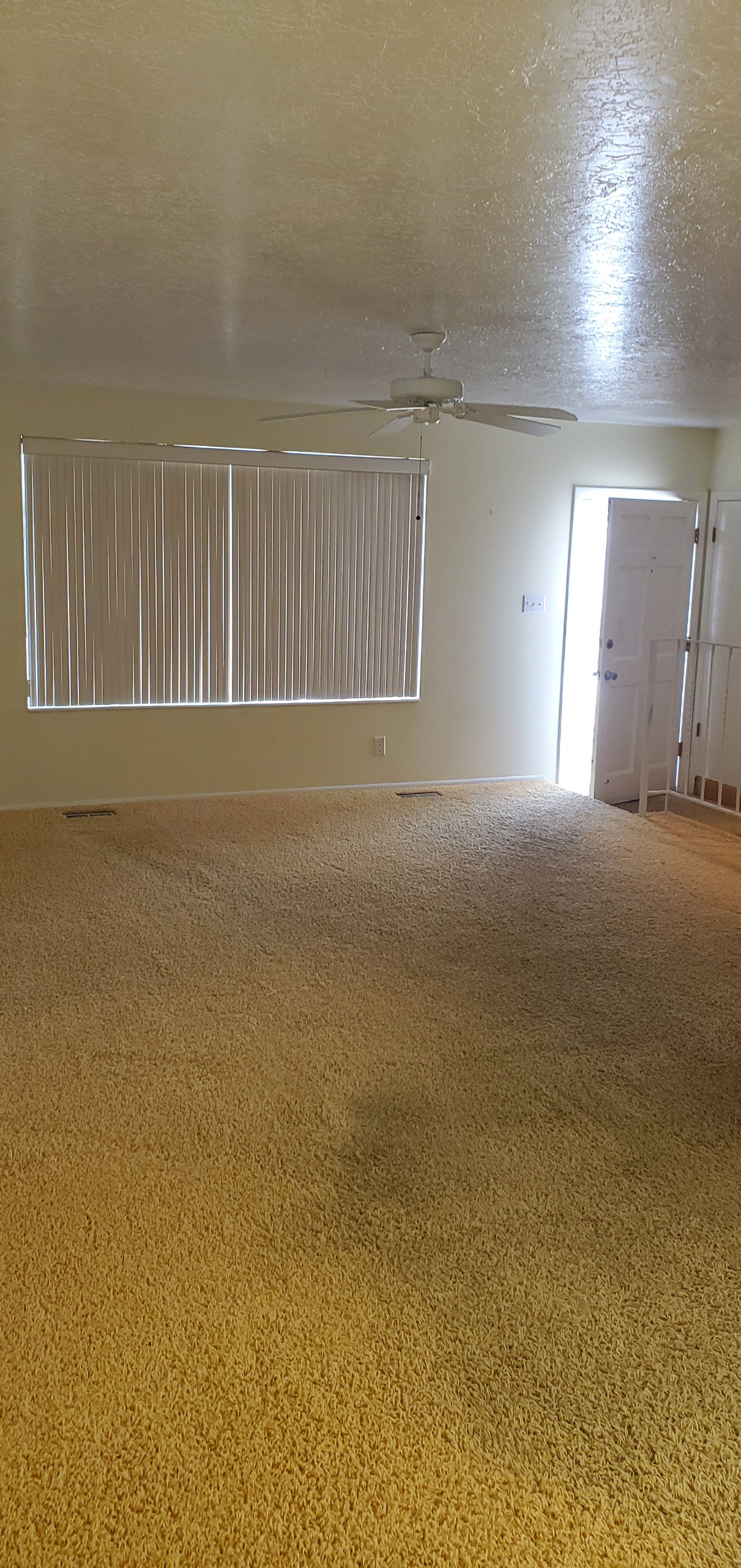 Spacious room featuring broadloom carpeting and window blinds