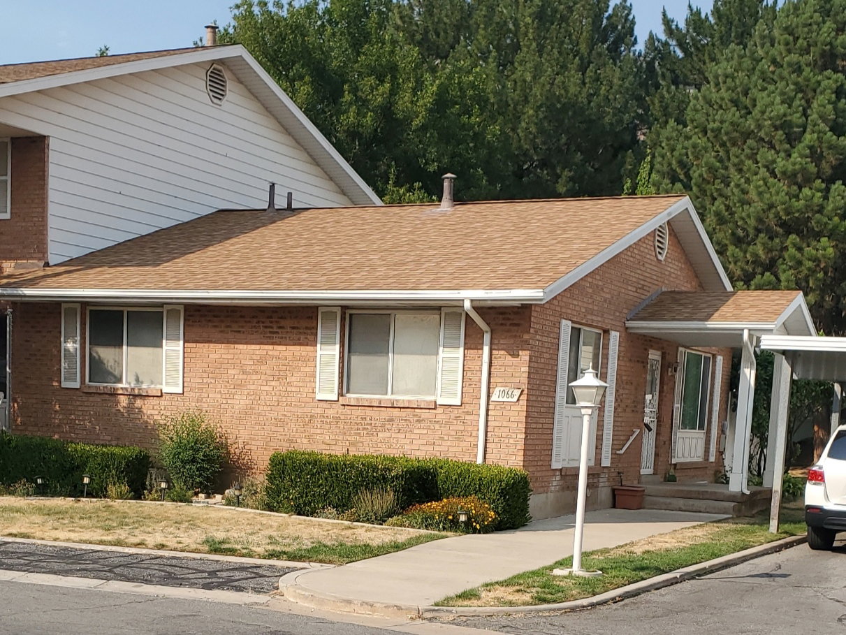 Brick exterior with white shutters and a tan shingle roof