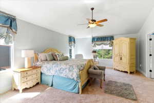 Bedroom featuring light wall color, carpet flooring, a ceiling fan, and multiple windows