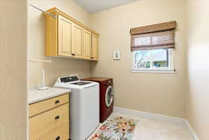 Laundry room featuring upper cabinetry with black hardware, a wood-finish counter with integrated drawers, and a window with a woven Roman shade