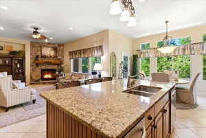 Open-concept kitchen and living area featuring an island with a double basin sink and stone-finish countertop