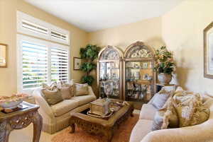 Room featuring a large window with plantation shutters, two arched glass-front display cabinets, and neutral wall paint